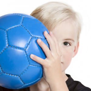 child smiling behind soccer ball